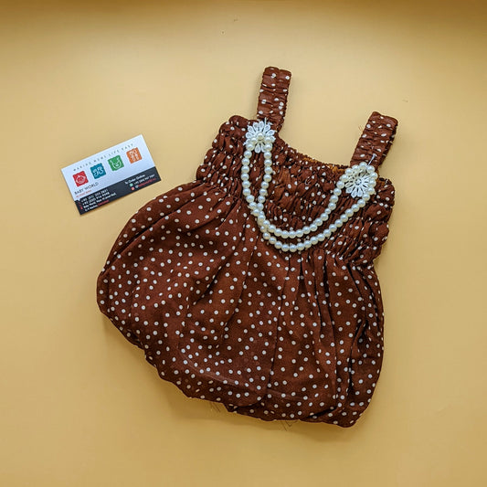 A brown dungare with white polka dots and a white pearl-like beaded strap and a card with color codes in the background.